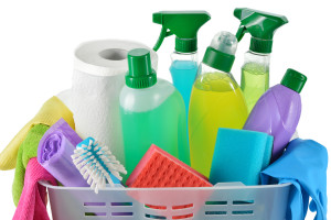Close up of cleaning products and supplies in a basket. Cleaners, microfiber cloths, gloves in a basket isolated on white background. Cleaning kit.